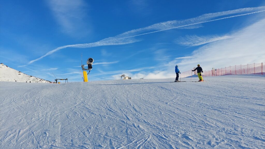 Drei Zinnen - pogled na skijašku stazu sa snježnim topom i skijašima na ski stazi
